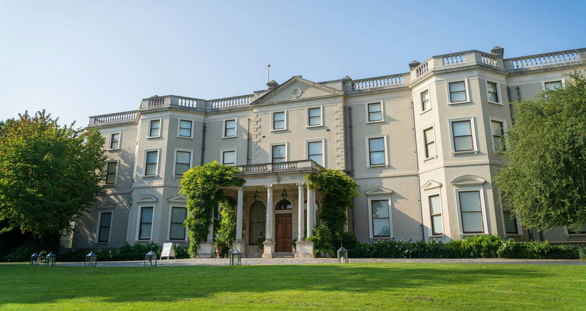Wide view of Farmleigh house, a historic house, estate and working farm is the official Irish state guest house, in Phoenix Park, Dublin, Ireland. Shot on a sunny day with blue skies and lots of foliage